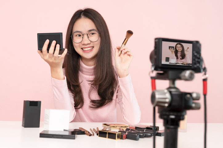 Woman professional beauty vlogger or blogger live broadcasting cosmetic makeup tutorial viral video clip by camera sharing on social media. Business online influencer on social media concept. Online Selling. Online Shopping