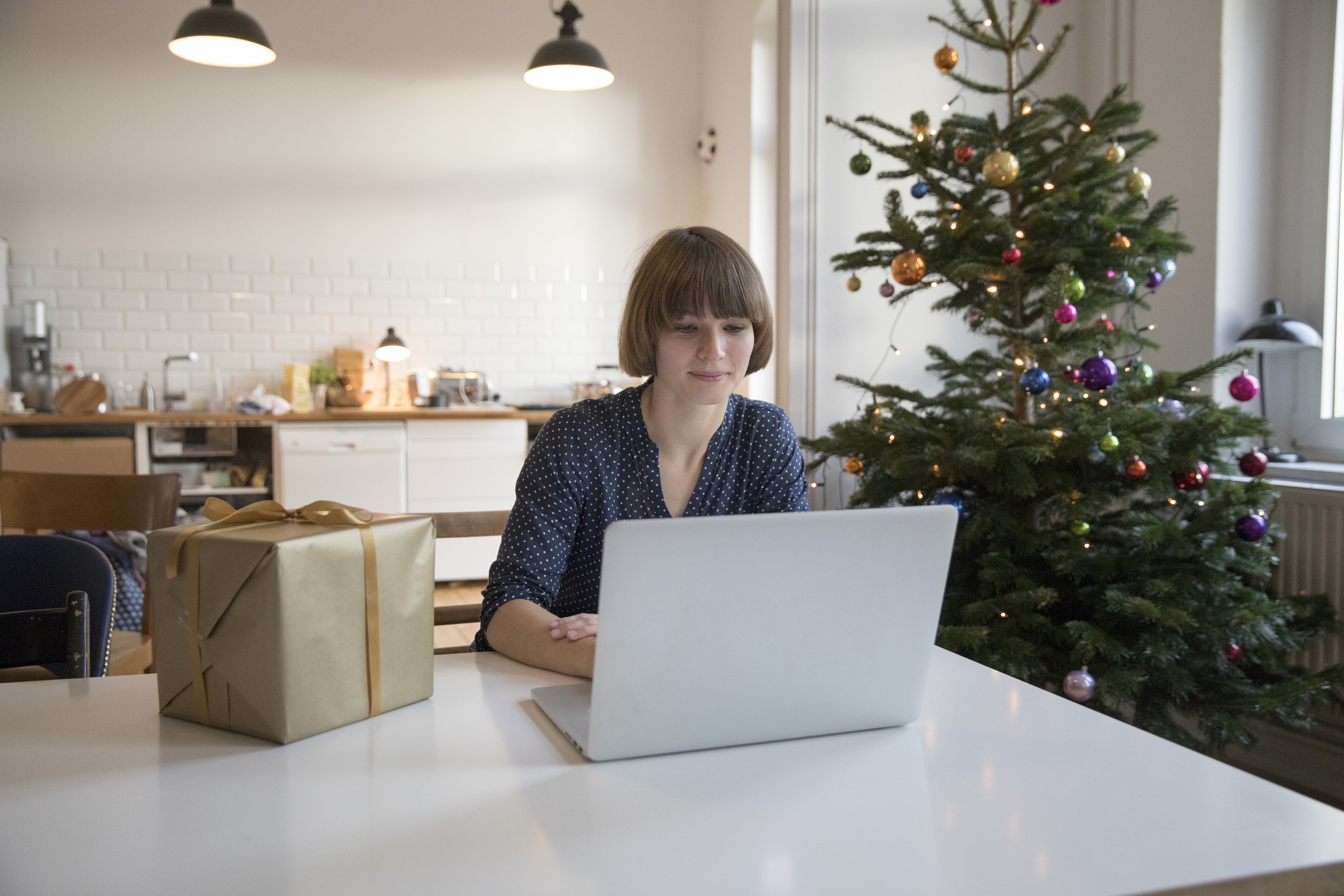 Girl sitting with her laptop - Xmas tree in background